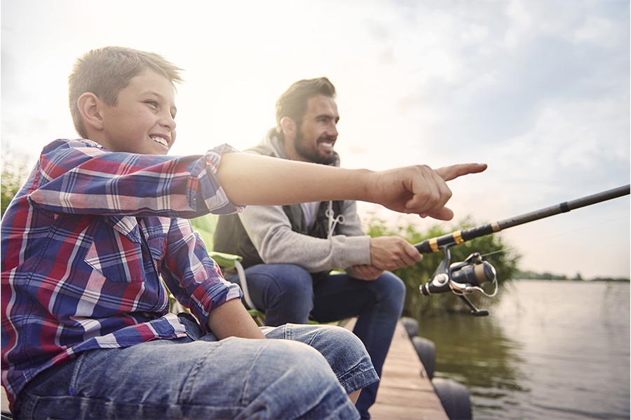 Personal Insurance - Father and Son Sitting on a Dock Fishing Together, Son Pointing into the Distance