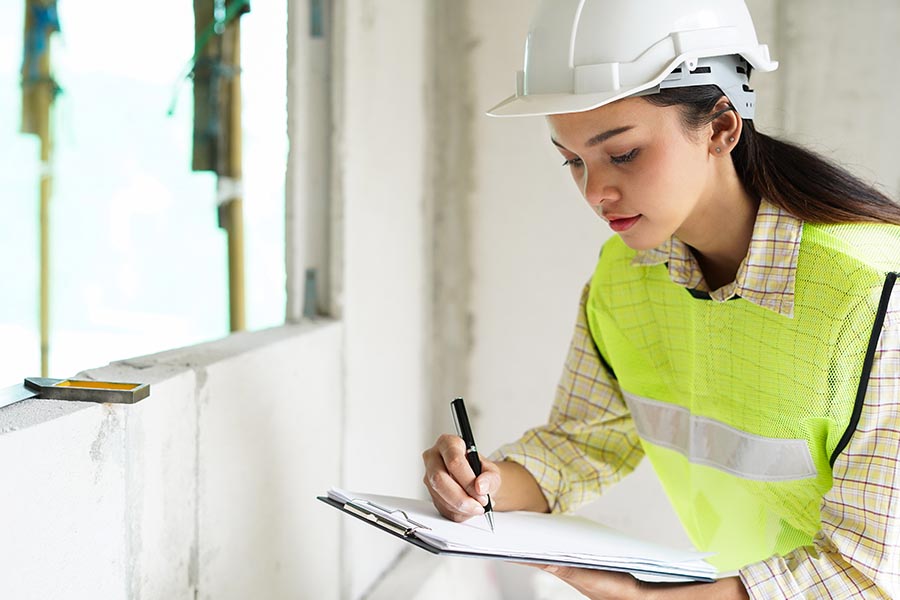 Specialized Business Insurance - Construction Worker Making Notes on a Clipboard, Wearing Safety Gear